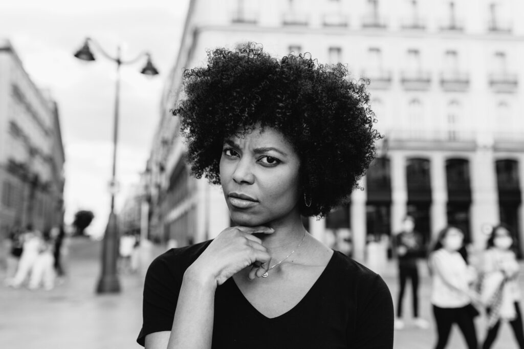 Pensive black woman on urban pavement in daytime